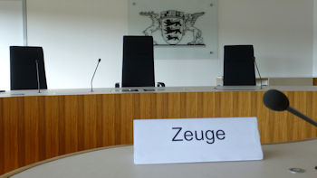 Foto - Blick auf den Richtertisch im Sitzungssaal des Landesarbeitsgerichts Baden-Württemberg mit Landeswappen im Hintergrund